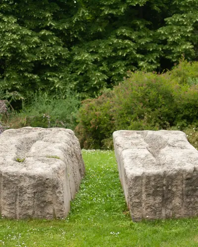 Zwei nebeneinander liegende Steinskulpturen aus Muschelkalk. Auf der Oberseiten befinden sich abstrakte Formen in den Stein gehauen.