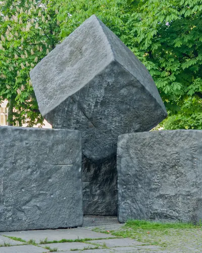 Vier aufeinander geschichtete in sich versetzte Steine in Würfelform aus dunkelgrauen Granit. Das Mahnmal fuer die Opfer des Faschismus des Künstlers Elmar Daucher auf dem Stuttgarter Karlsplatz. Weitere Informationen im Text