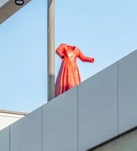 Ein rotes Kleid in Epoxidharz gegossen als kinetische Skulptur auf dem Dach des Hauses der Geschichte. Es kann auf einer Schiene hinundherfahren.