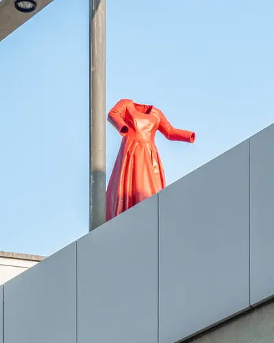 Ein rotes Kleid in Epoxidharz gegossen als kinetische Skulptur auf dem Dach des Hauses der Geschichte. Es kann auf einer Schiene hinundherfahren.