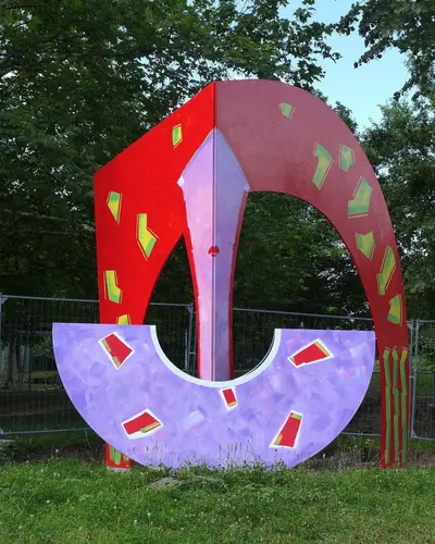 Stahlskulptur in Lila, Rot, Weiß, mit grell grünen rechteckigen Elementen bemalt.